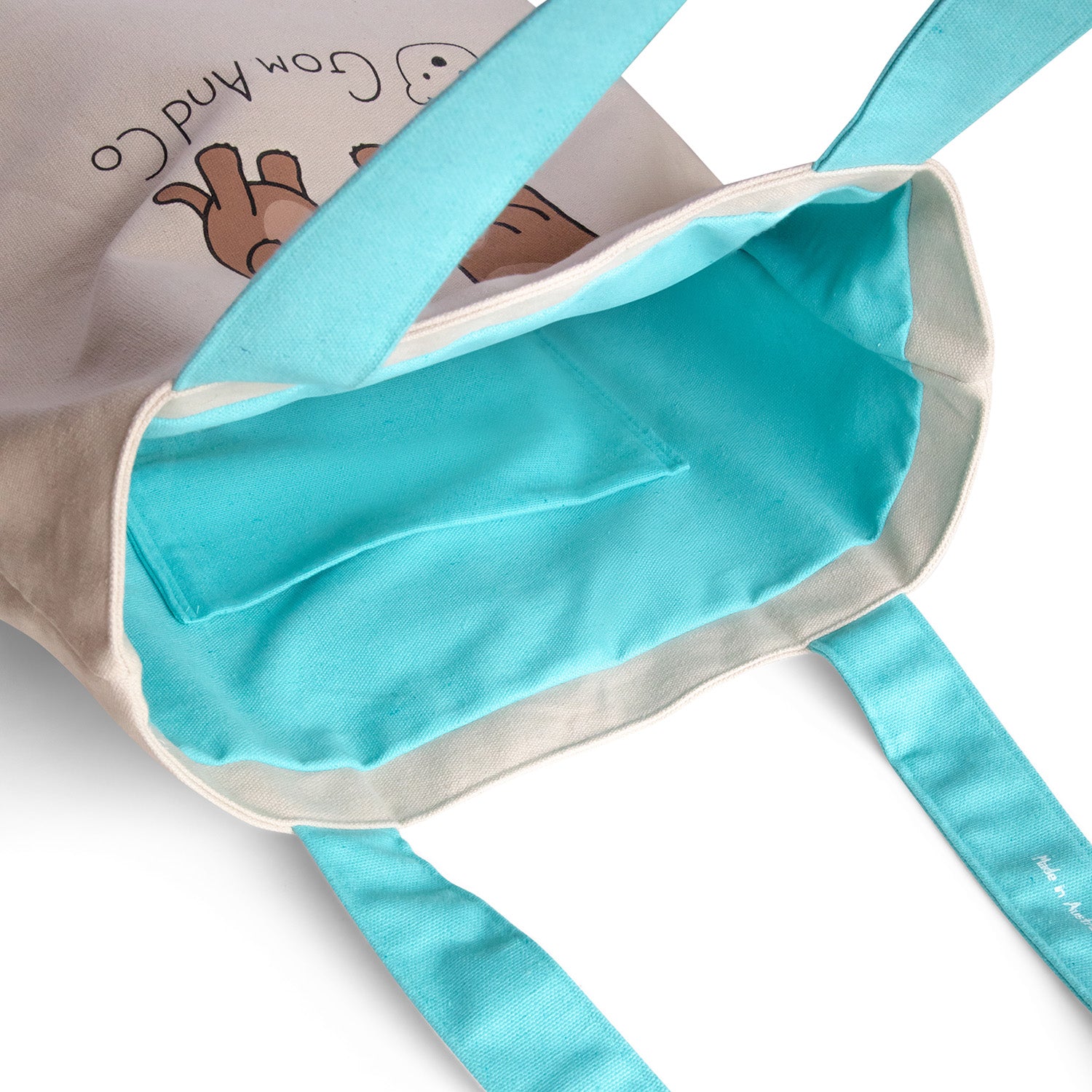 A canvas tote bag with aqua coloured handles and aqua lining. Two otters are shown holding hands on both sides.